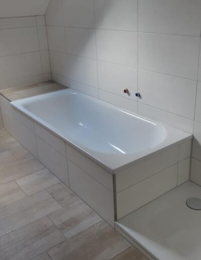 Ein Badezimmer mit naturfarbenen Fliesen und einer Badewanne und Dusche.